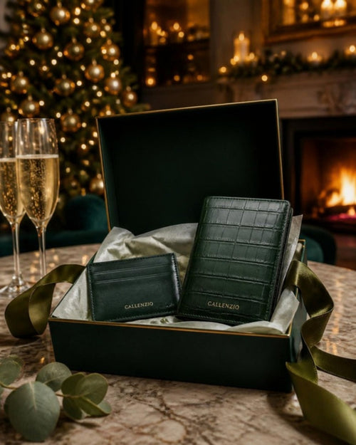 Callenzio Geschenkset in der Geschenkbox vor Kaminfeuer und Weihnachtsbaum, daneben zwei Sektgläser