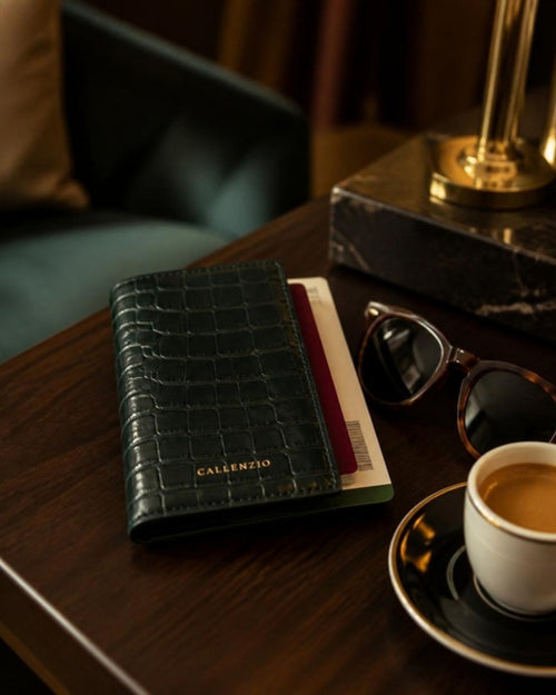 Callenzio Passhülle mit Reisepass und Bordkarte auf dunklem Holztisch in einer Hotel-Lounge